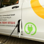 Elektrofahrzeug mit Ladekabel, das an eine Ladesäule an einem Firmenwagen angeschlossen ist.