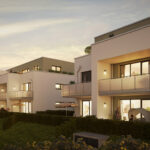 Moderne Wohnanlagen mit Balkonen, umgeben von Gärten, bei Sonnenuntergang beleuchtet.