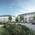 Moderne Wohngebäude mit Bäumen, Parkplatz und Spaziergängern, unter blauem Himmel.